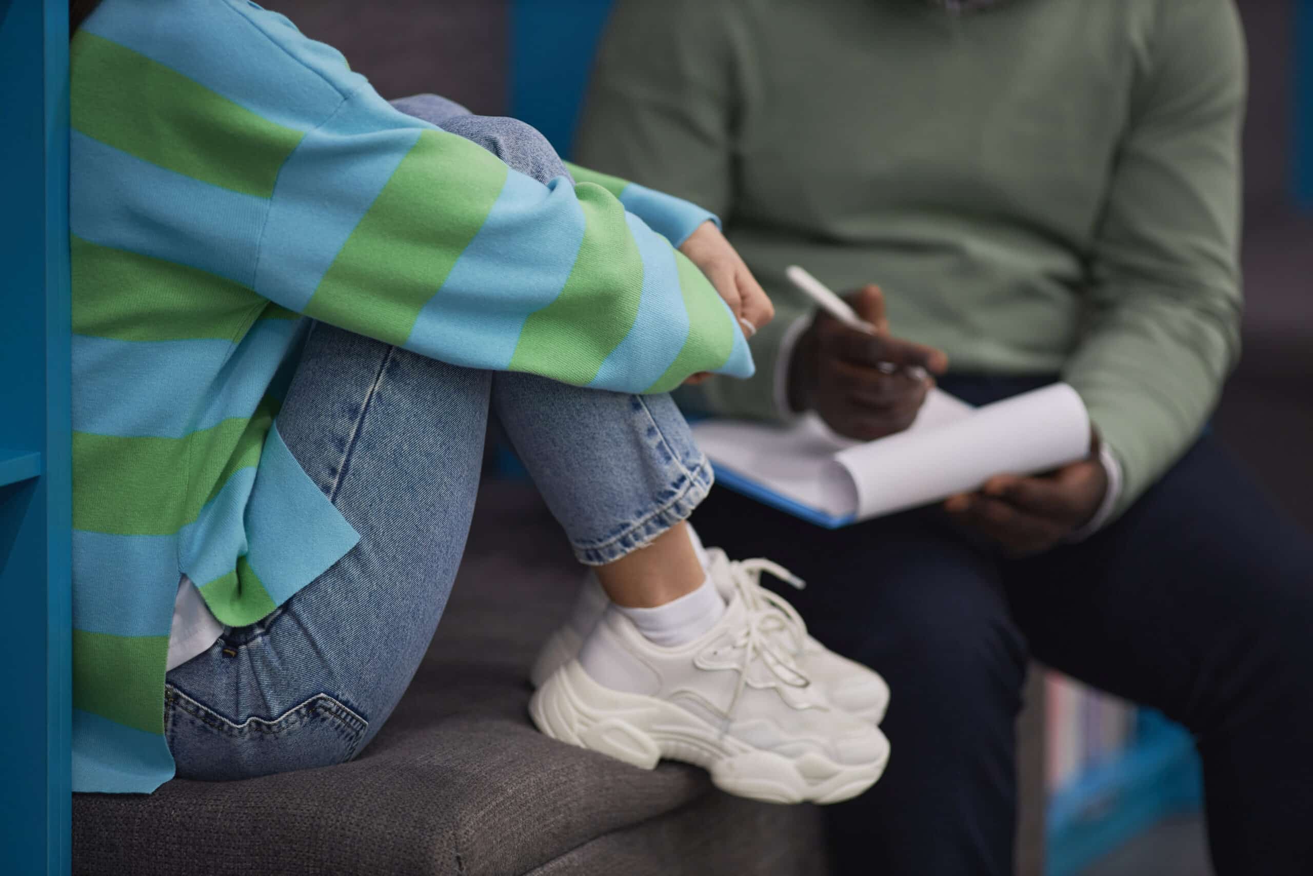 Closeup of stressed teenage girl talking to mental health therapist in session